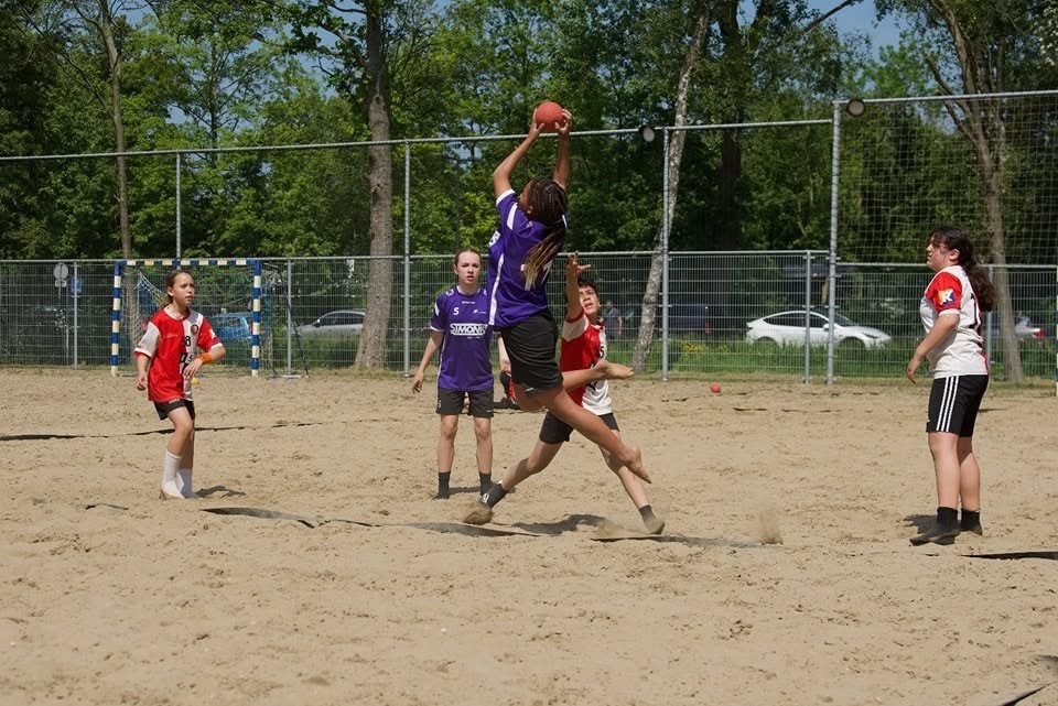 Speler springt voor een schot op het zand